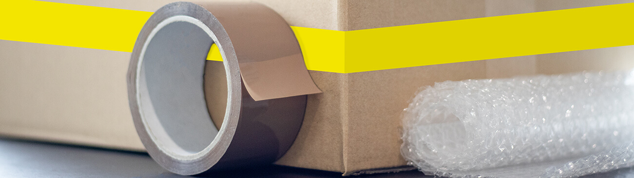 Adhesive tape, bubble wrap and moving boxes on a table